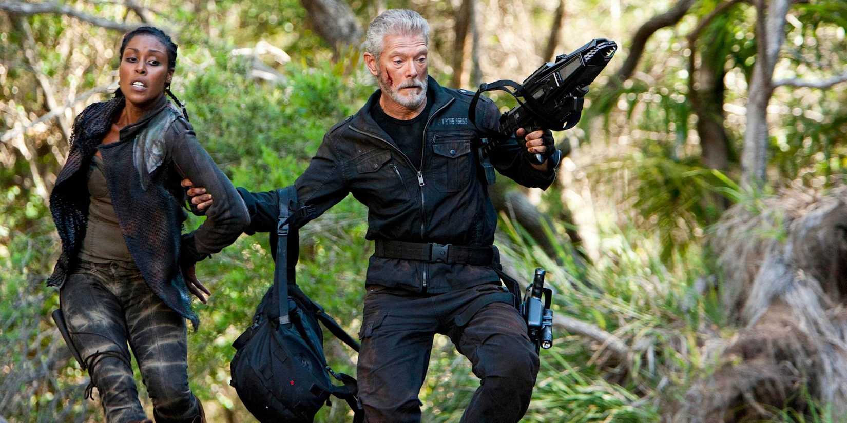 Commander Nathaniel Taylor leading Mira by the arm through a forest in Terra Nova