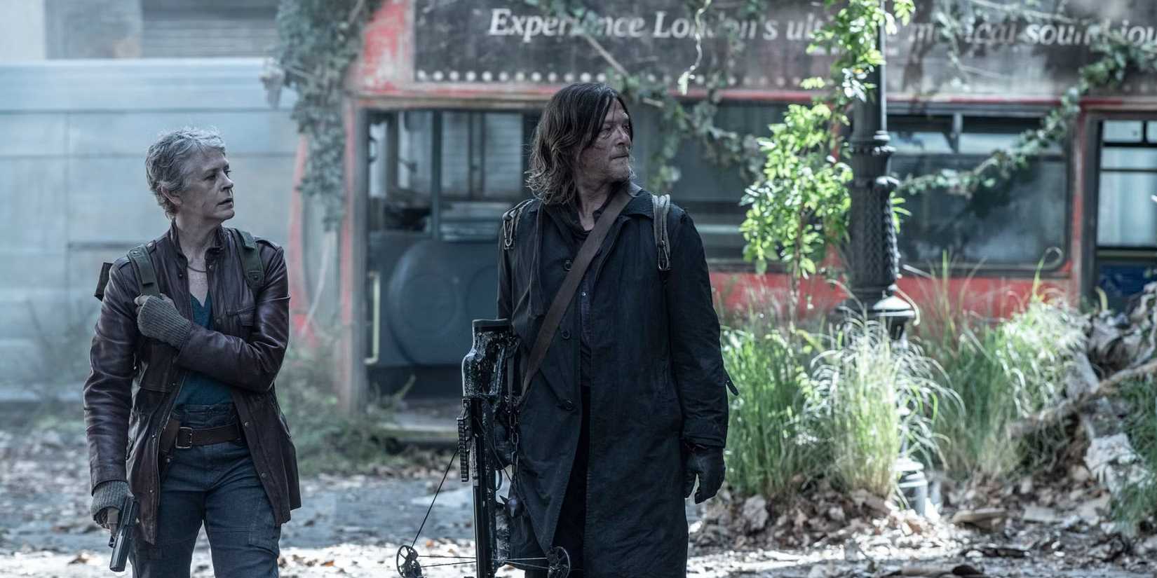Norman Reedus as Daryl and Melissa McBride as Carol walking through London and passing an abandoned bus in The Walking Dead: Daryl Dixon season 3