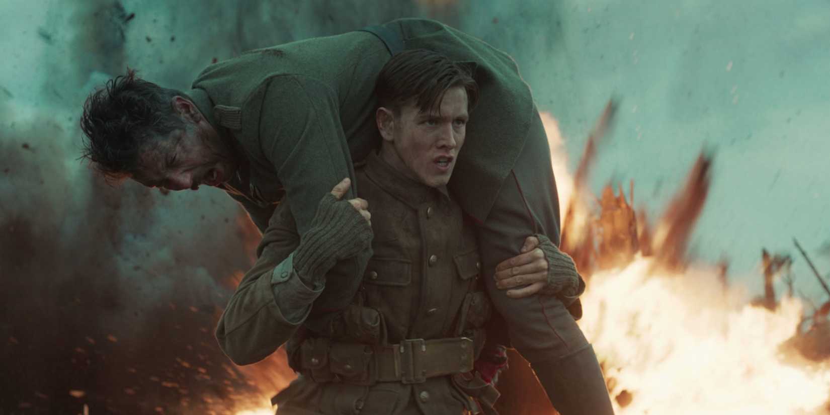 Harris Dickinson carrying a wounded soldier as an explosion goes off behind them in The King's Man