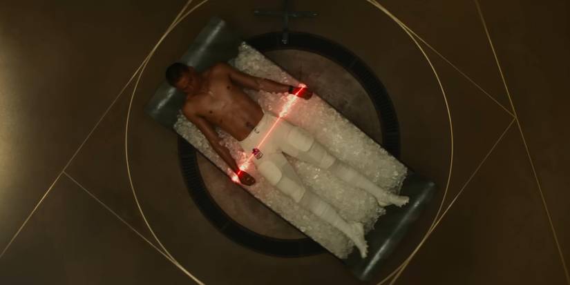 Him trailer shot of the main character lying in ice with a red light over his legs