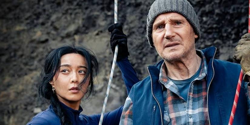 Liam Neeson and Bingbing Fan holding onto ropes next to a rock face in Ice Road Vengeance 
