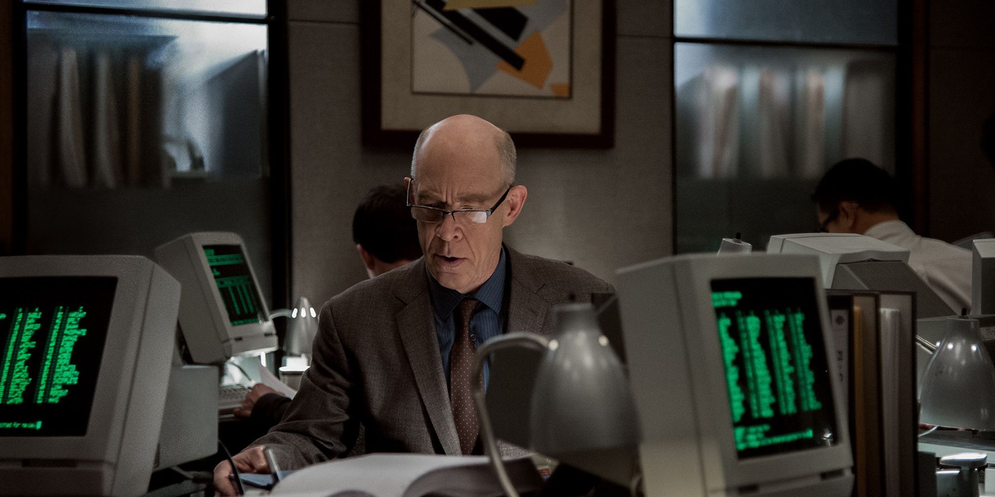 J.K. Simmons nei panni di Howard Silk in Counterpart mentre lavora a una scrivania circondato da vecchi computer