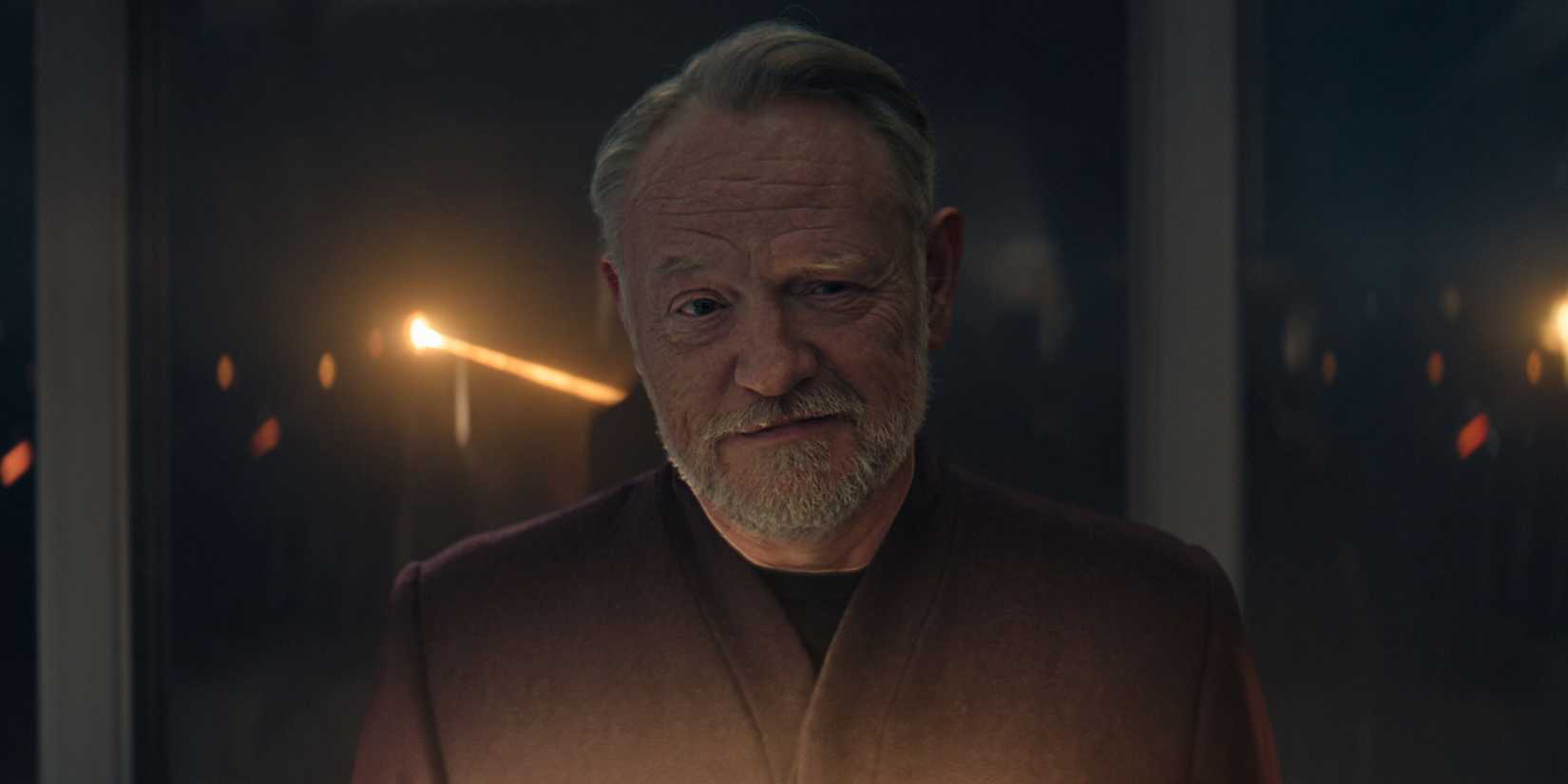jared harris as hari seldon smirking and standing in front of a gladd window away from it in foundation