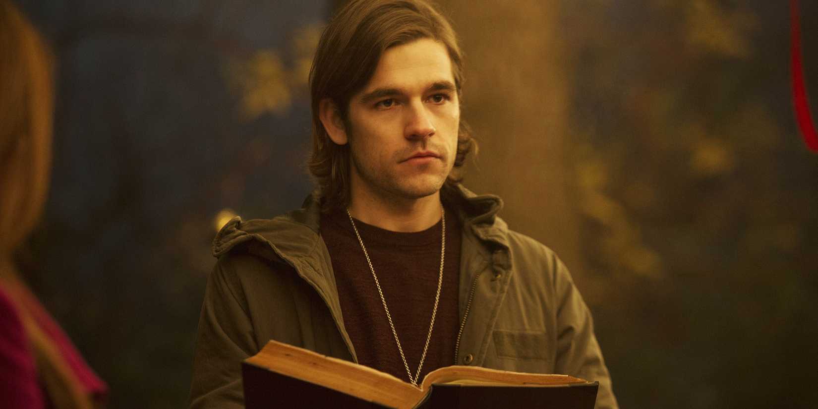 Jason Ralph como Quentin Coldwater segurando um livro em The Magicians.