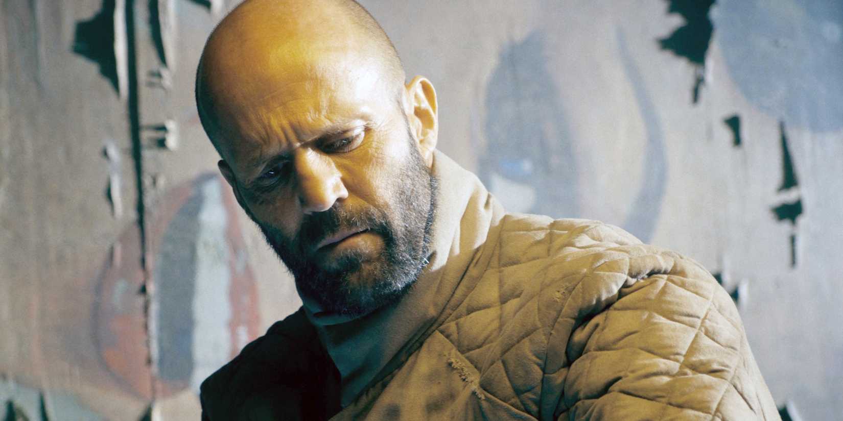 Jason Statham looks down with a grave expression in a scene from The Beekeeper