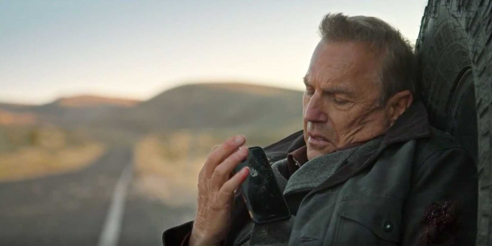 John Dutton holding his cellphone, leaning against his pickup truck after he's been shot in Yellowstone season 3