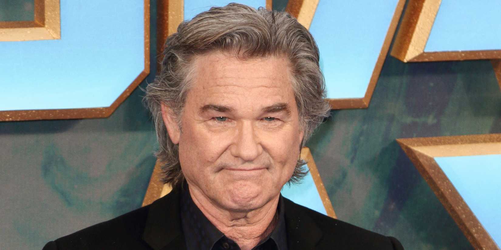 Kurt Russell looks forward while slightly grinning at a red carpet event