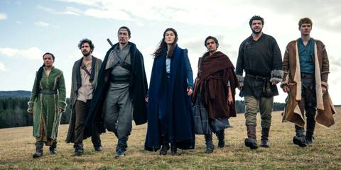 Left to Right Nynaeve, Mat, Lan, Moiraine, Egwene, Perrin, and Rand walking together in an open field