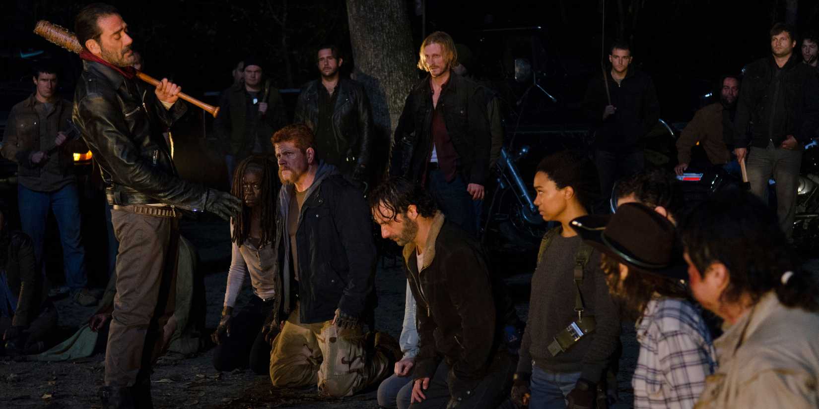 Negan holding his bat and deciding who to beat with it as the captives are held hostage on the ground in The Walking Dead