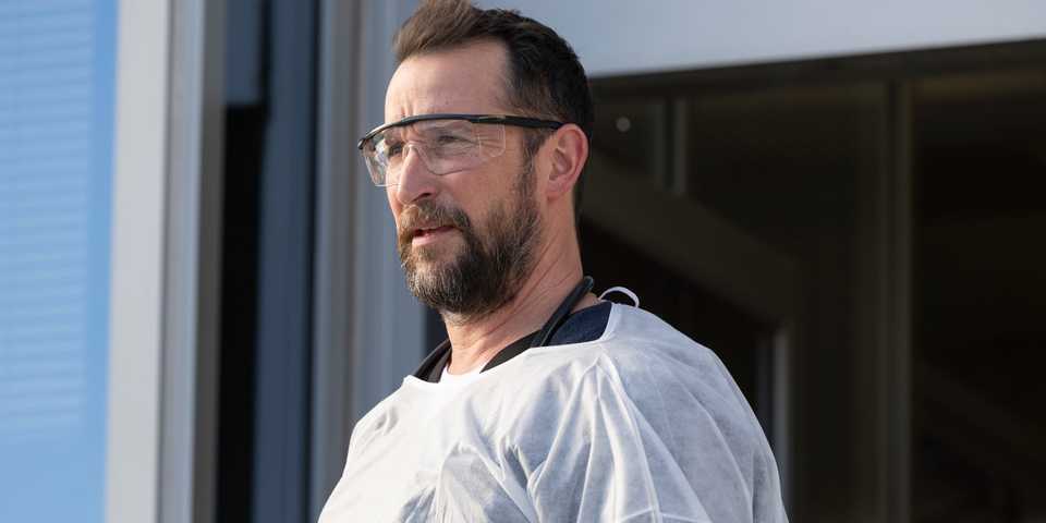 Noah Wyle as Dr. Michael 'Robby' Robinavitch looking at someone in The Pitt