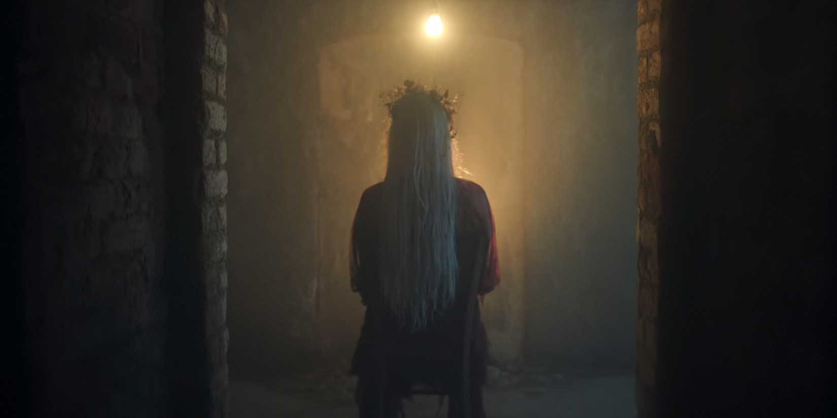 Ophelia Frump with her back turned to the camera sitting in a chair in Wednesday season 2 finale