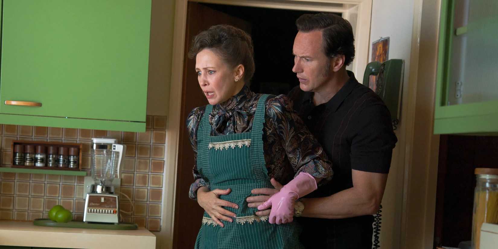 Patrick Wilson and Vera Farmiga as Ed and Lorraine Warren cowering in a kitchen doorway in The Conjuring Last Rites