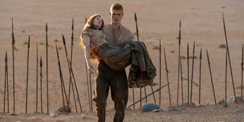Rand holding an unconscious Moiraine, spears sticking up from the ground behind them, in The Wheel of Time season 3 episode 4