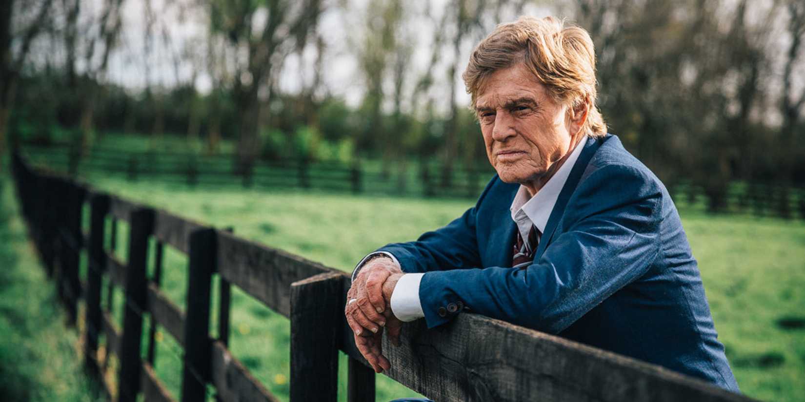 Robert Redford standing by a fence in The Old Man & the Gun