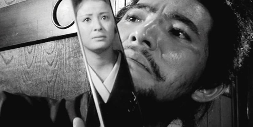 A woman's reflection is shown in a sword as a man looks on in Samurai Wolf
