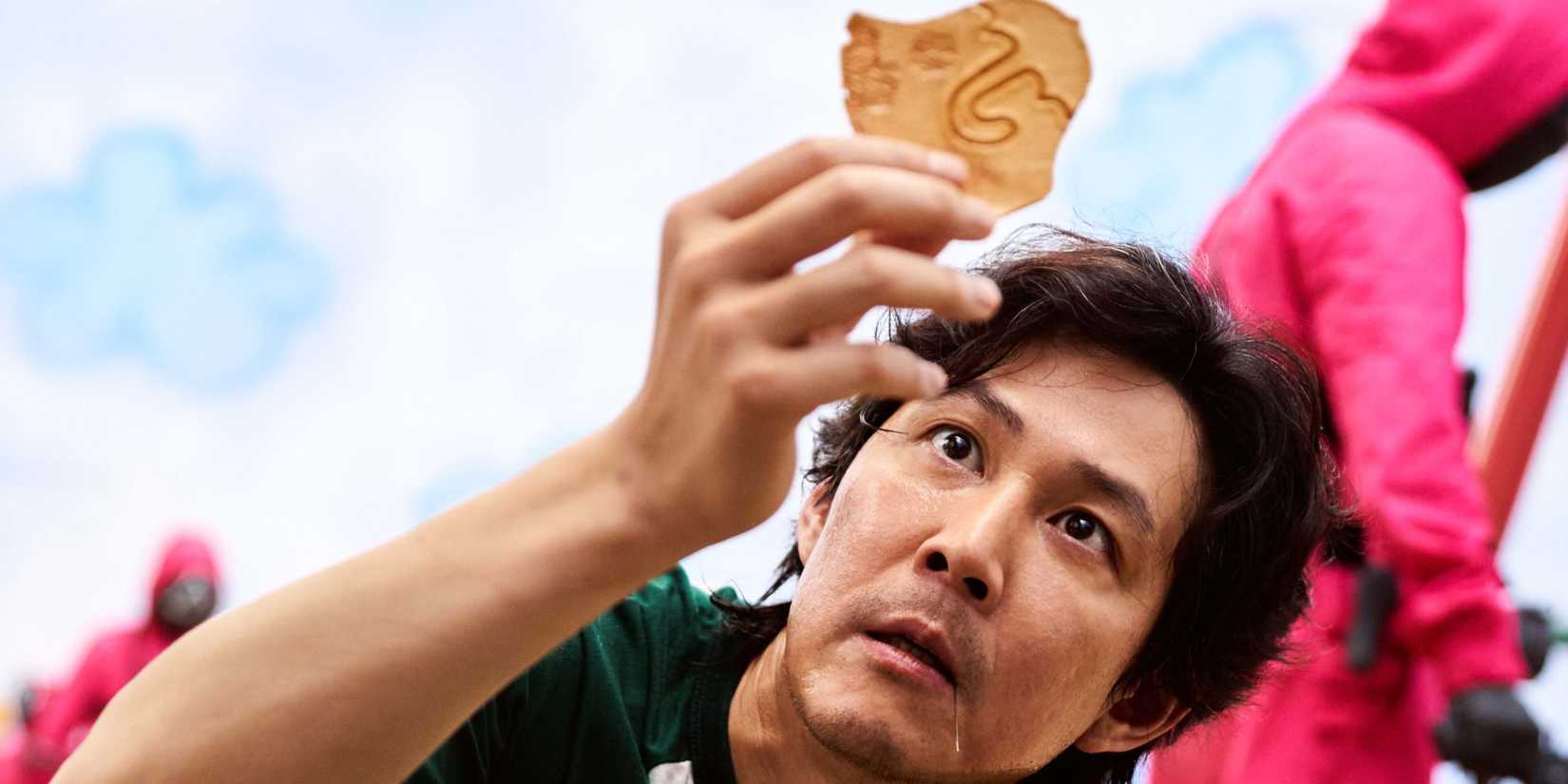 Seong Gi-hun (Lee Jung-jae) holding up a cookie in Squid Game