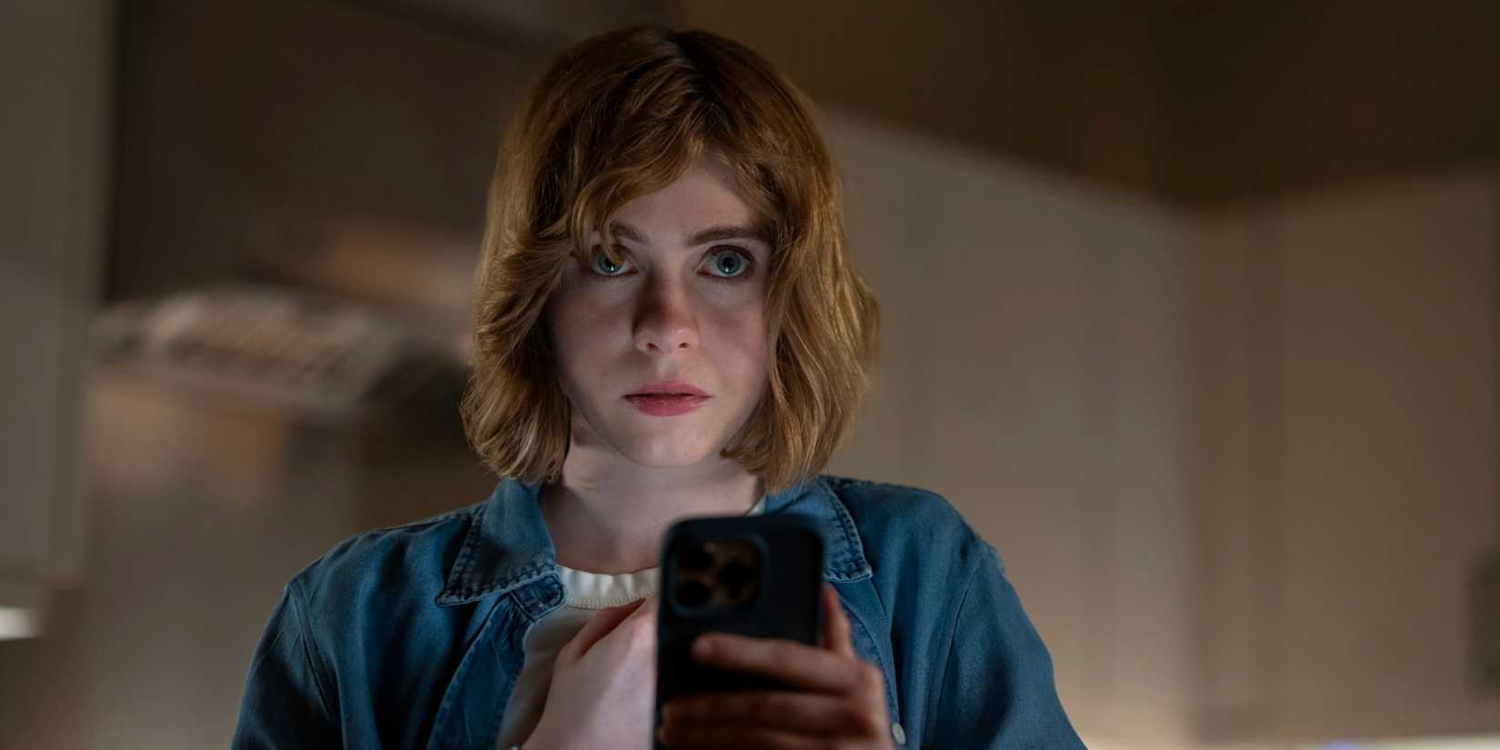 Sophia Lillis looking at her phone in The Chair Company