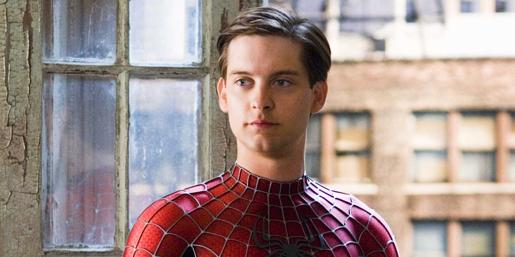 Peter Parker looks on blankly while wearing his Spider-Man suit near a window in Spider-Man 3