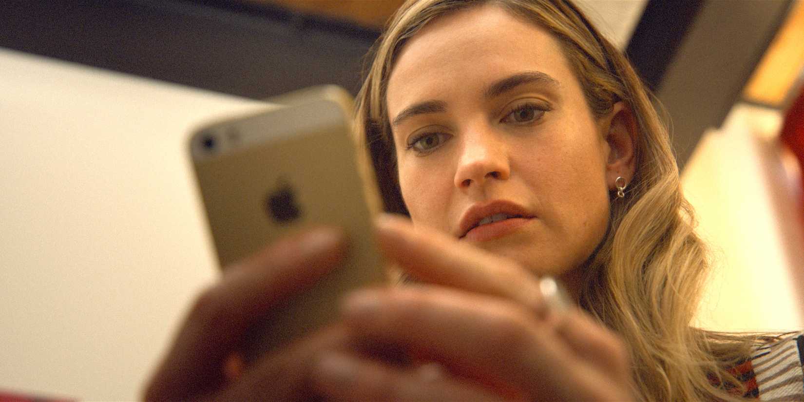 Lily James as Whitney Wolfe Herd looking down at her phone in Swiped