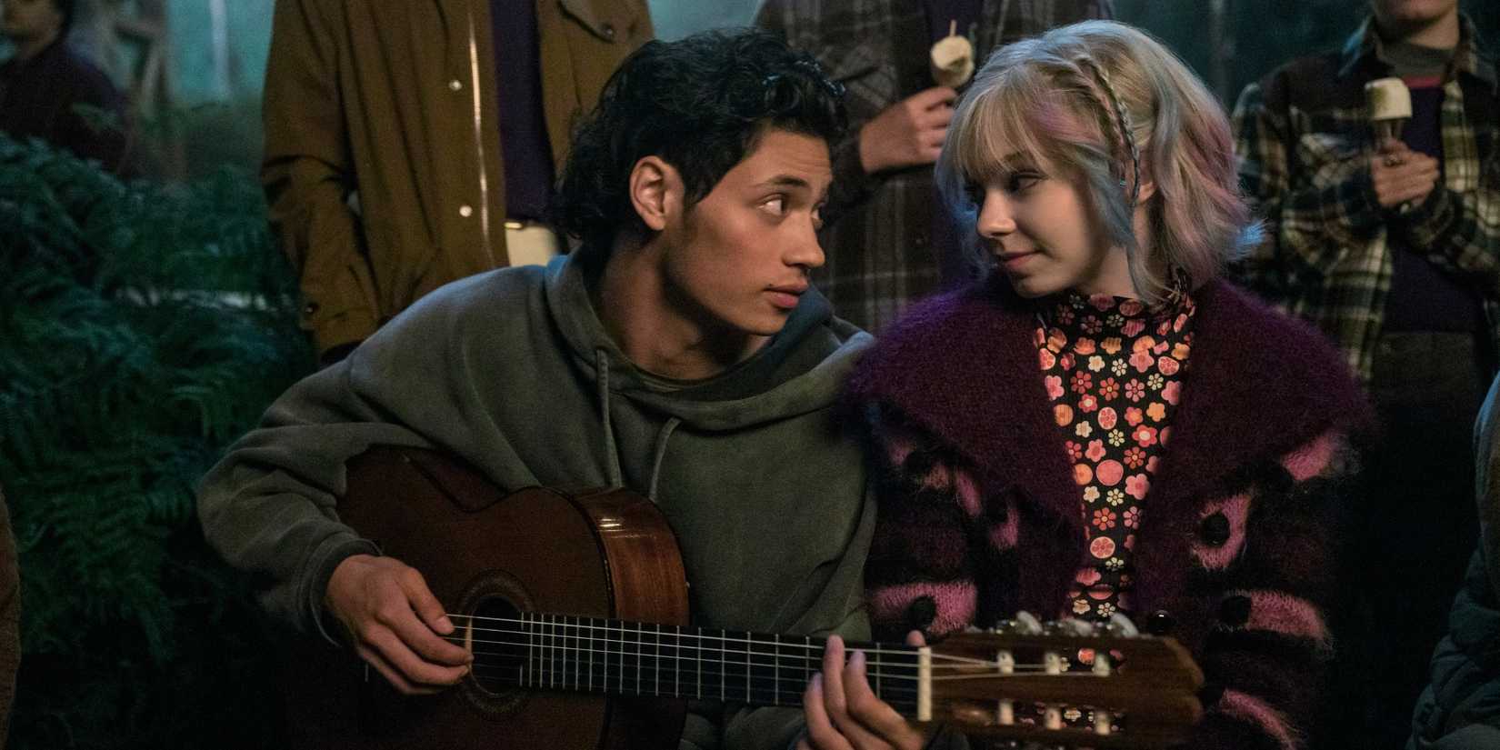 Bruno playing the guitar while looking lovingly at Enid in Wednesday season 2