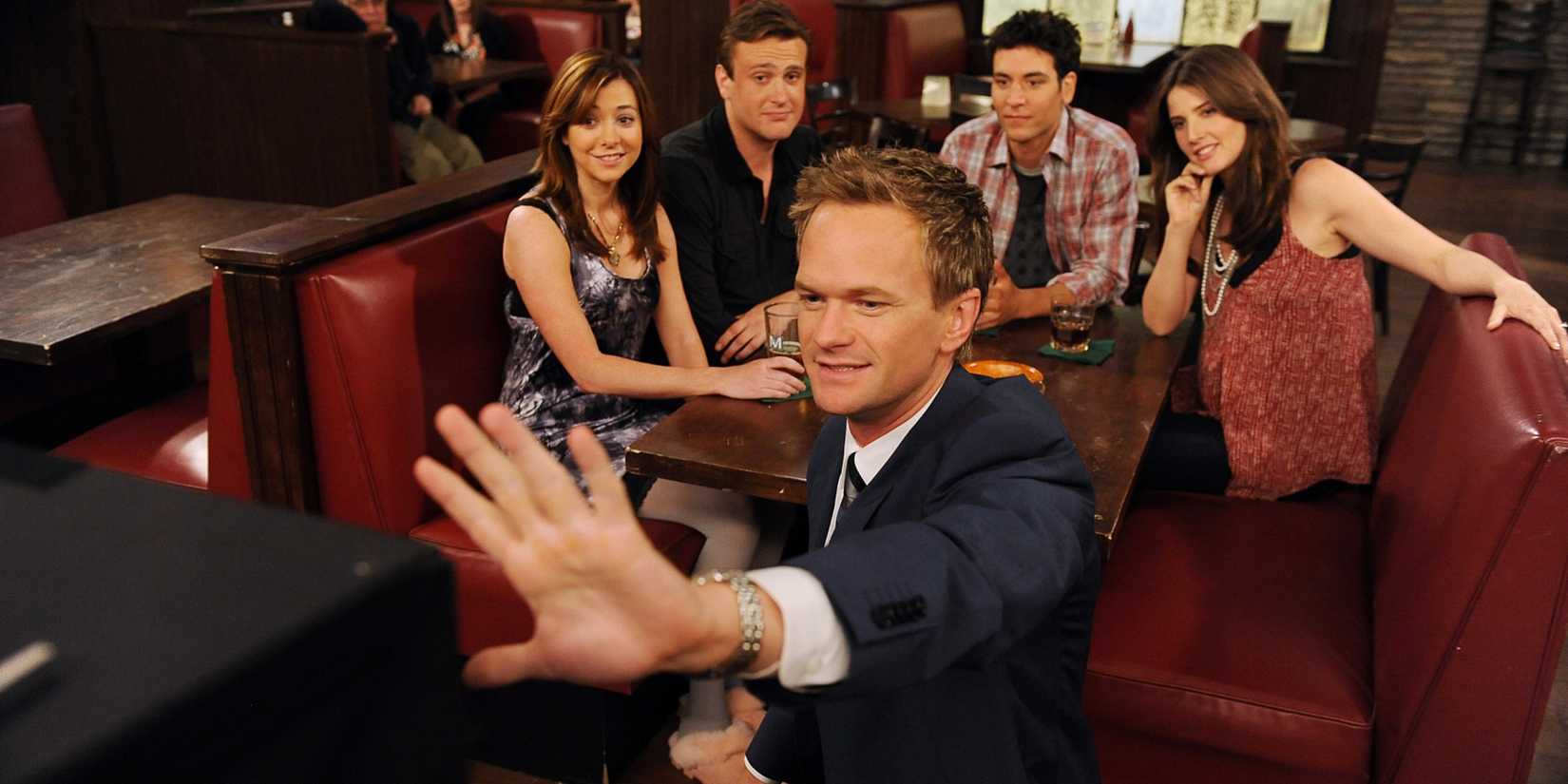 Ted e a turma sentados em seu estande no Maclaren's com Barney com a mão levantada em How I Met Your Mother