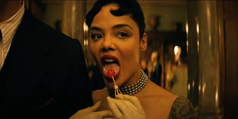 Tessa Thompson licks a cherry on a toothpick in Hedda