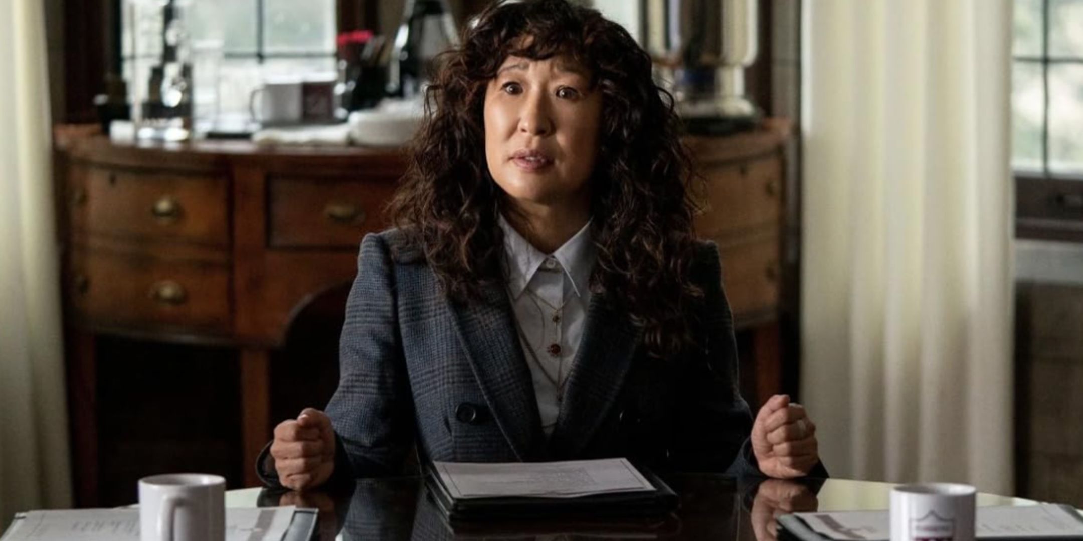 Sandra Oh seduta a una scrivania
