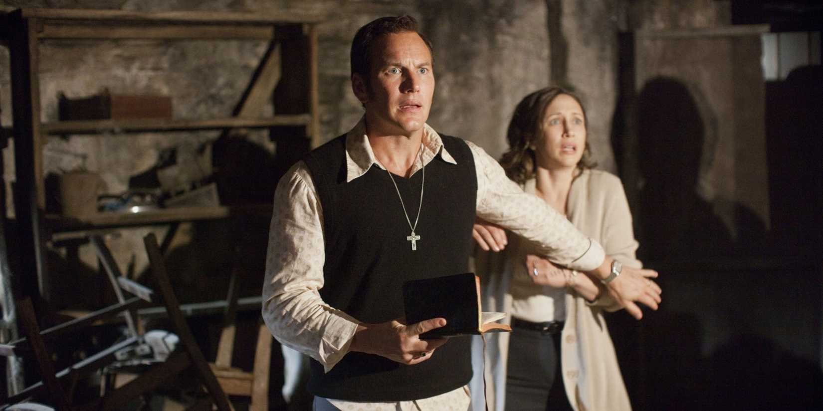 Ed and Lorraine cower in fear while looking offscreen in The Conjuring