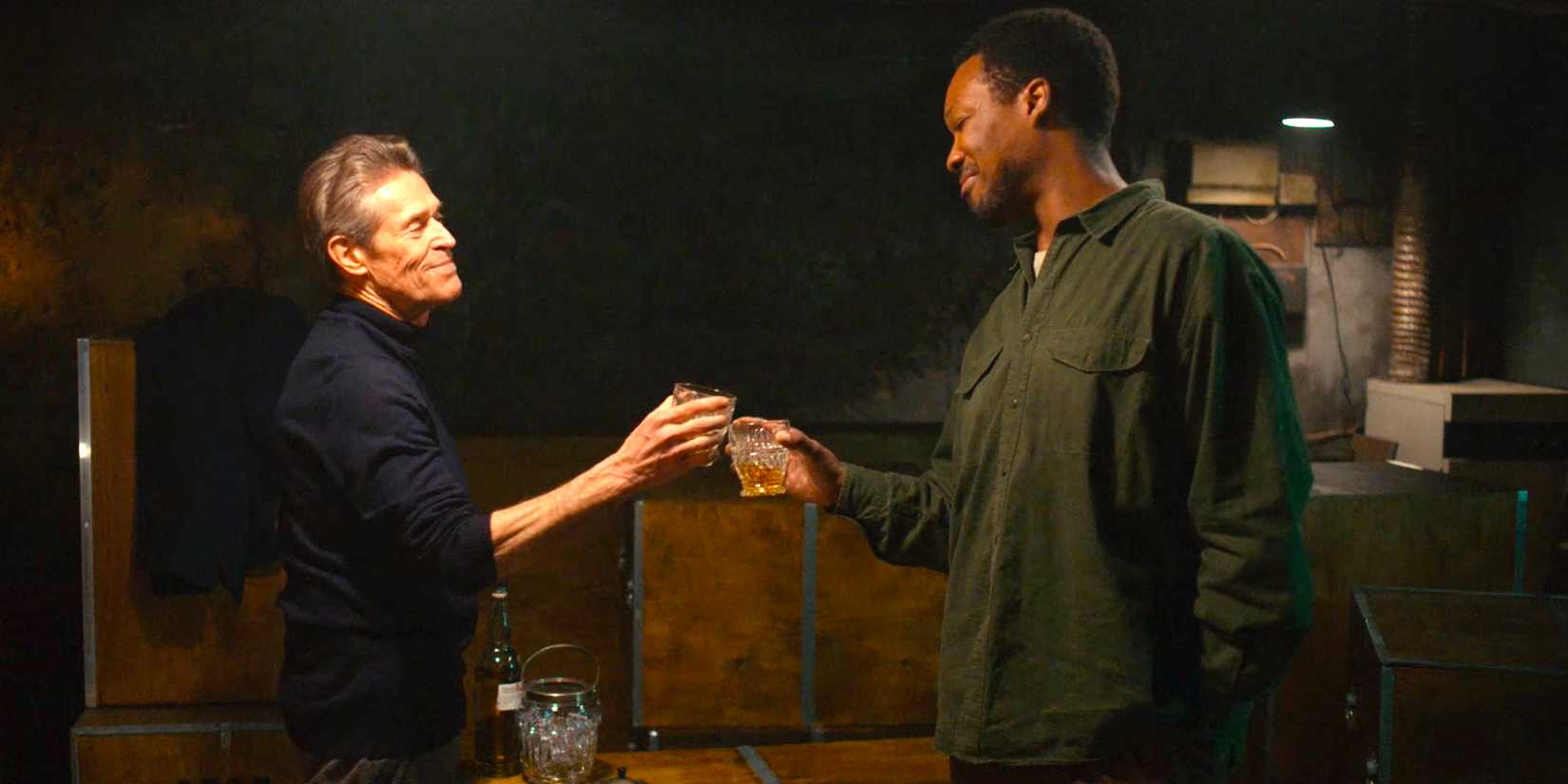 Willem Dafoe and Corey Hawkins toasting one another in The Man in My Basement