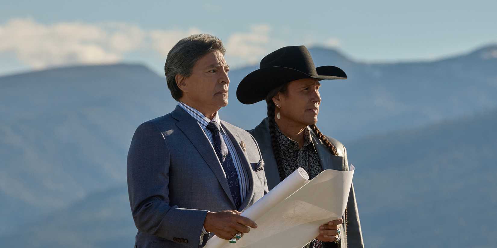 Thomas Rainwater and Mo Brings Plenty standing against the mountains in Yellowstone