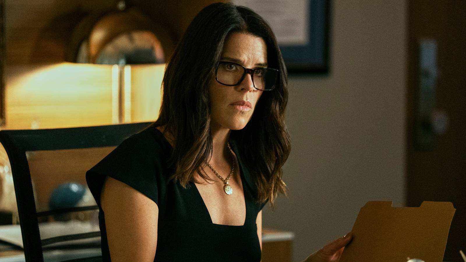Maggie McPherson, played by Neve Campbell, sits at her desk in The Lincoln Lawyer season 1