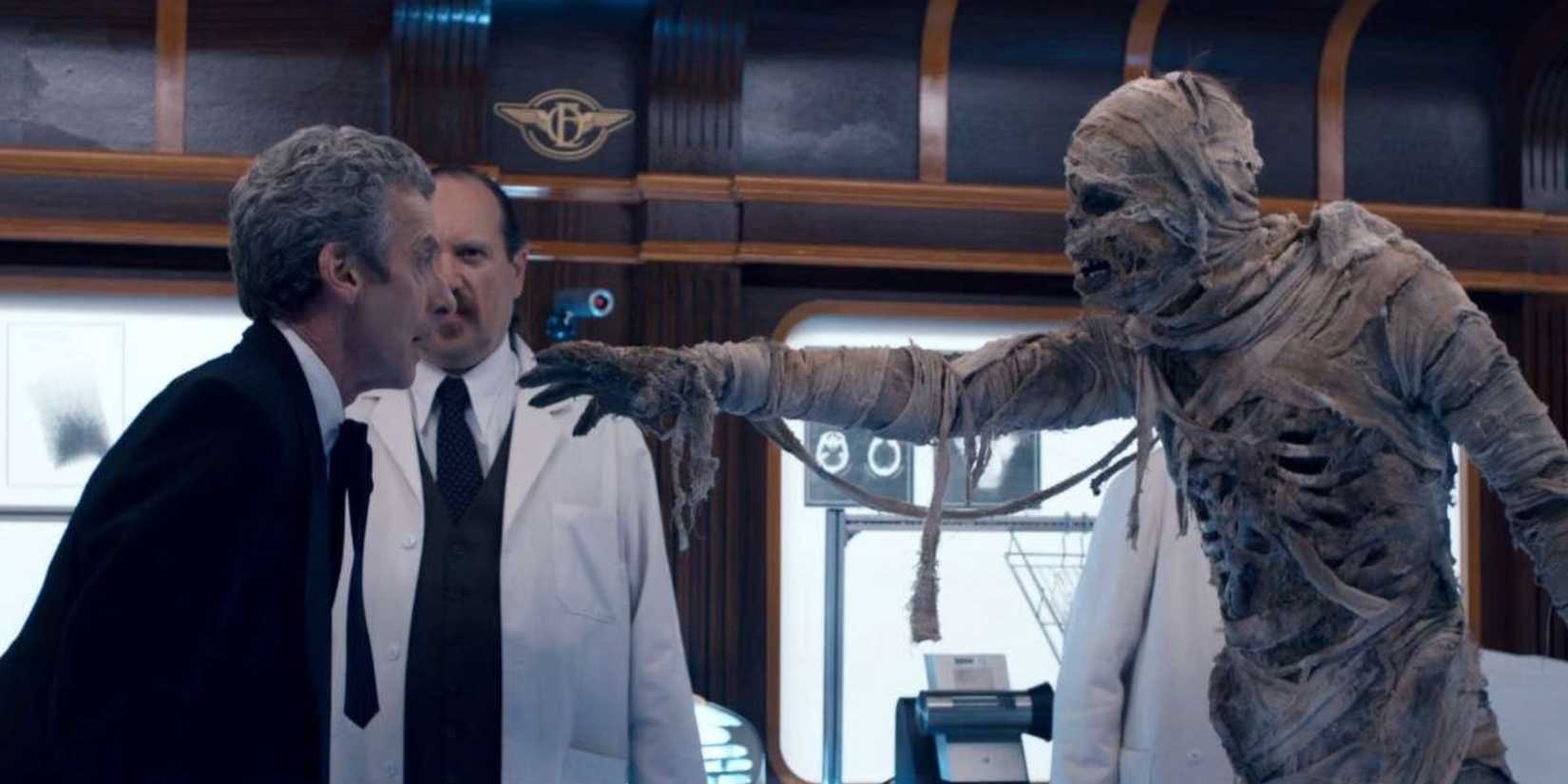 The Twelfth Doctor facing the mummy on the train, who is reaching an arm out towards him, in the Doctor Who episode “Mummy on the Orient Express.” 