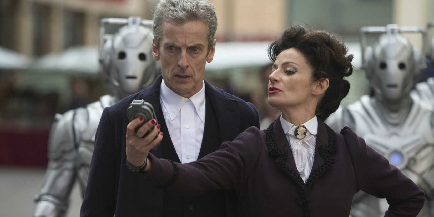 The Twelfth Doctor looking shocked and Missy posing as they stand with Cybermen behind them in the Doctor Who episode "Death In Heaven."