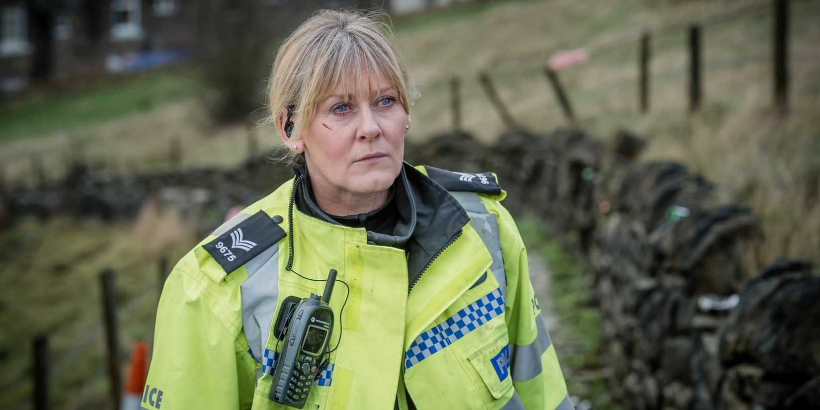 Sarah Lancashire as Sgt Catherine Cawood, standing outside someone's house in a police uniform, with a cut on her cheek in Happy Valley.