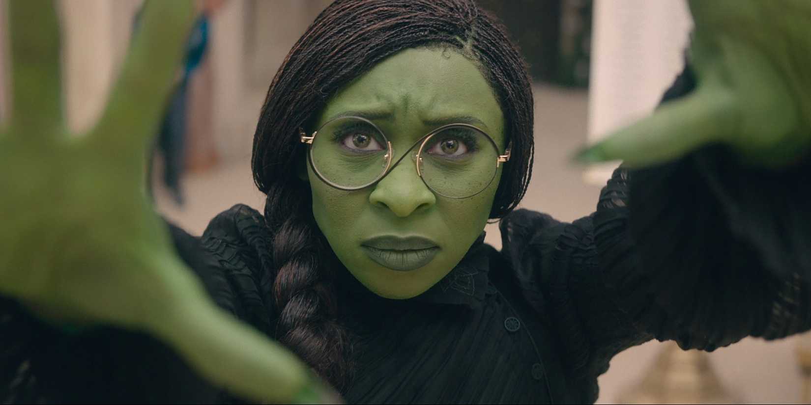 Elphaba holding her hands up, using her powers in the Shiz courtyard, in Wicked.