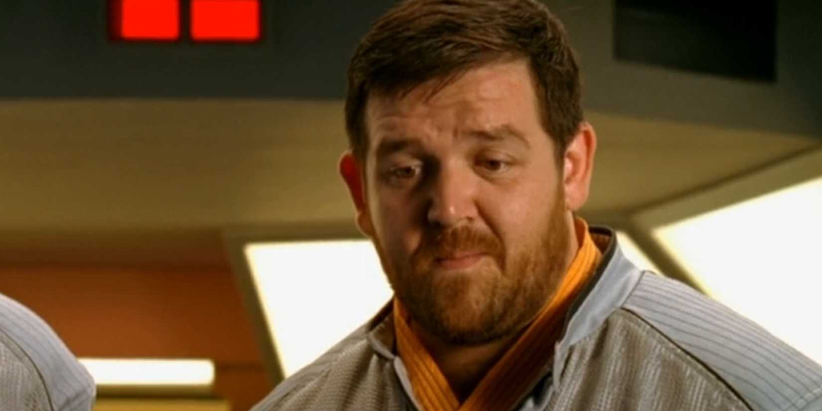 Nick Frost as Mike Henderson staring at something downwards, looking perplexed, in Hyperdrive.