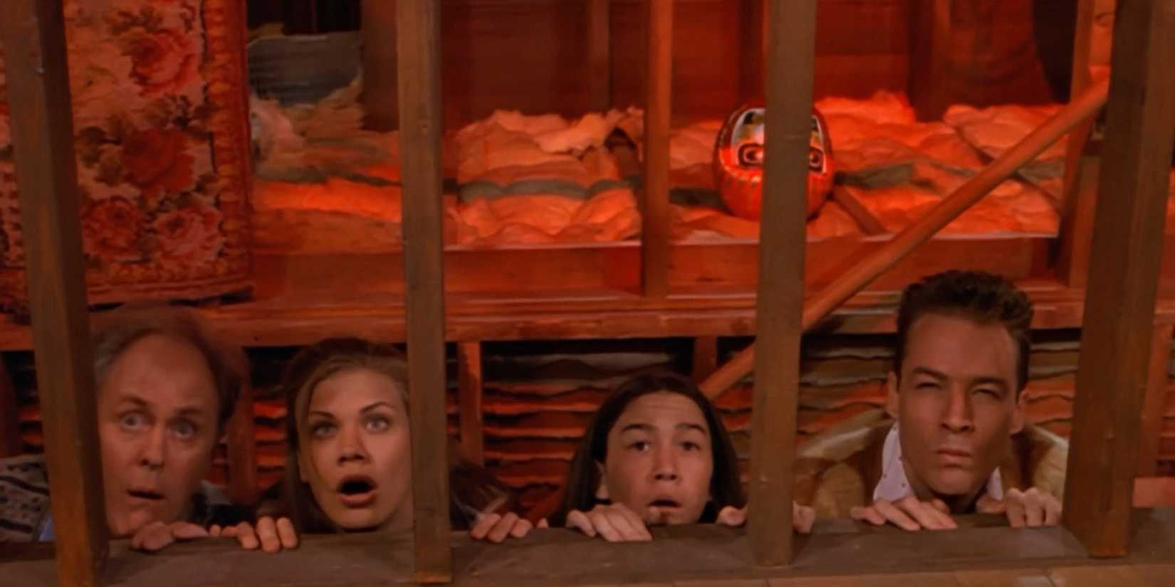 Dick, Sally, Tommy, and Harry kneeling down on the floor and peering through a gap in 3rd Rock from the Sun.