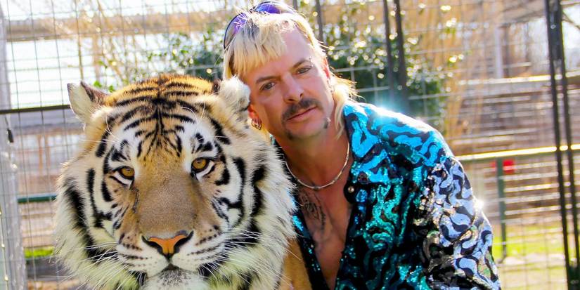 Joe Exotic leaning against a large tiger