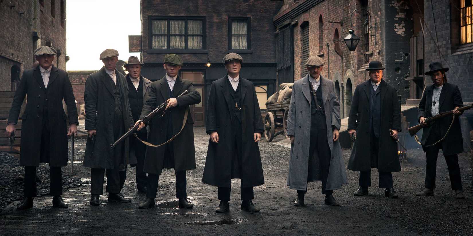 The main characters in Peaky Blinders in a dark street, holding weapons