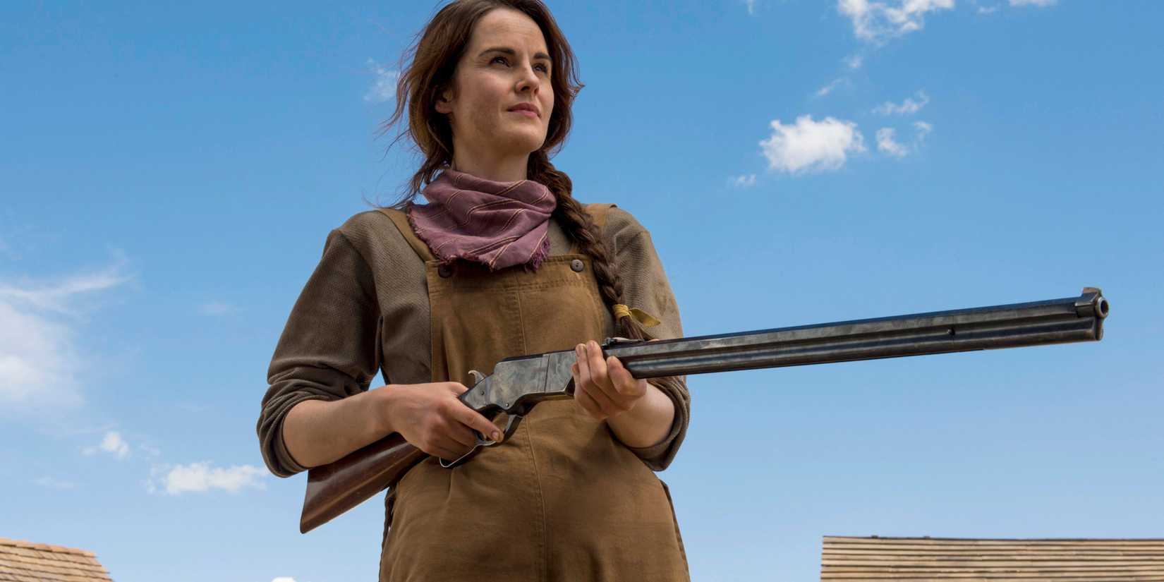 Upward shot of Michelle Dockery as Alice Fletcher standing with a rifle in hand in Godless
