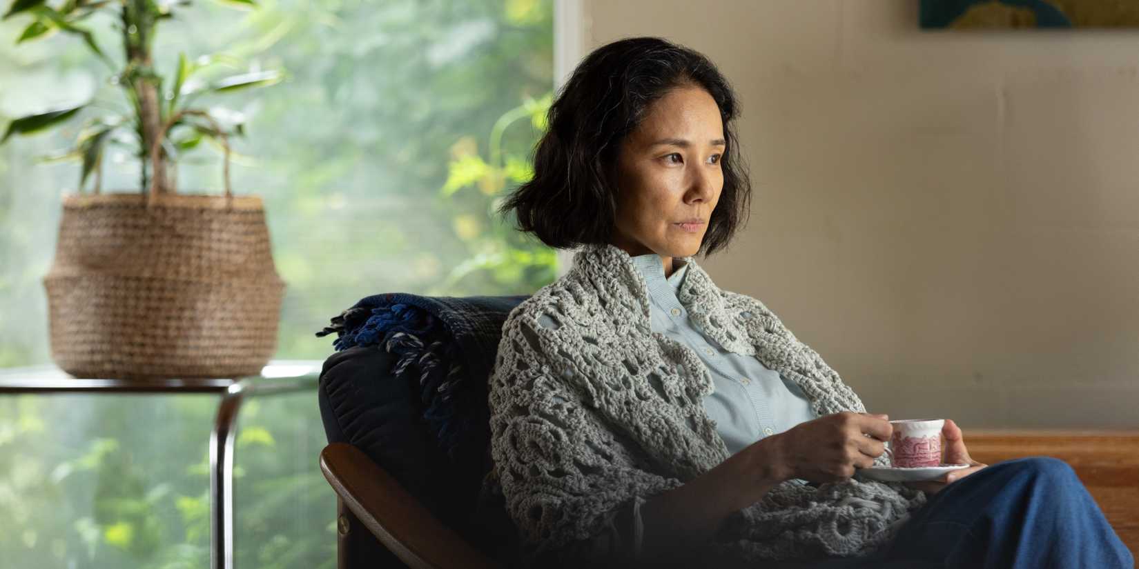 Yoh Yoshida sitting in a chair with a cup of tea in A Pale View of Hills
