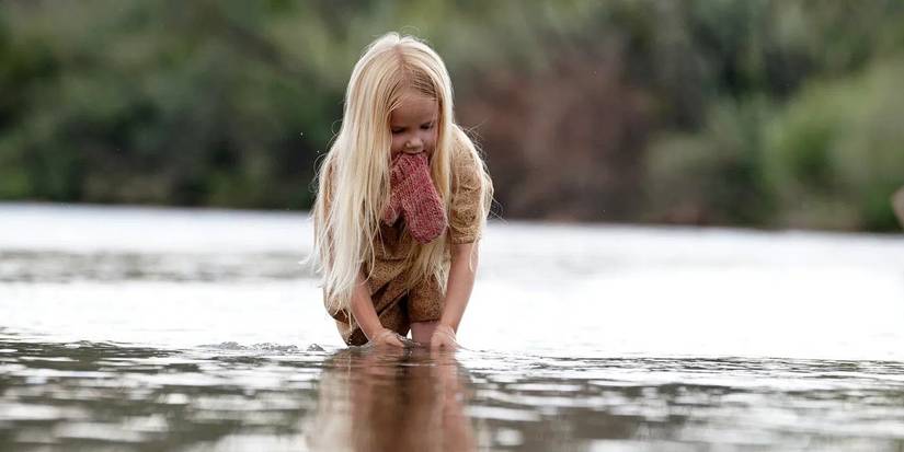 A little girl kneeling over water in Killing Faith