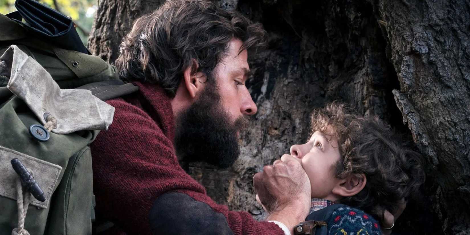 John Krasinski como Lee cobrindo a boca assustada de Marcus (Noah Jupe) em Um Lugar Silencioso