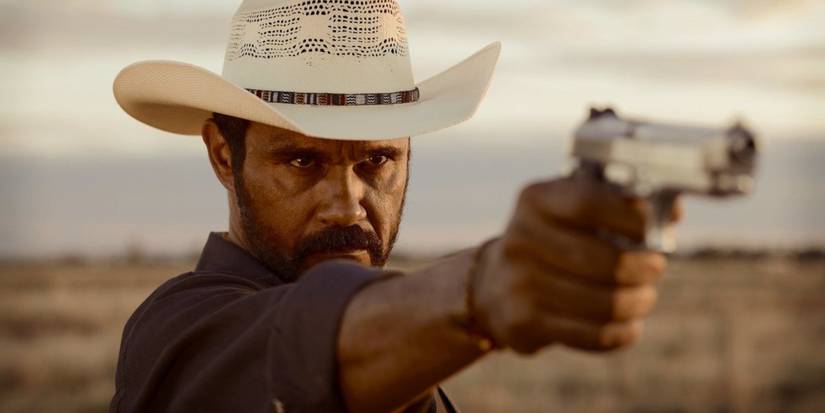 Aaron Petersen dramatically points a gun in a scene from Mystery Road