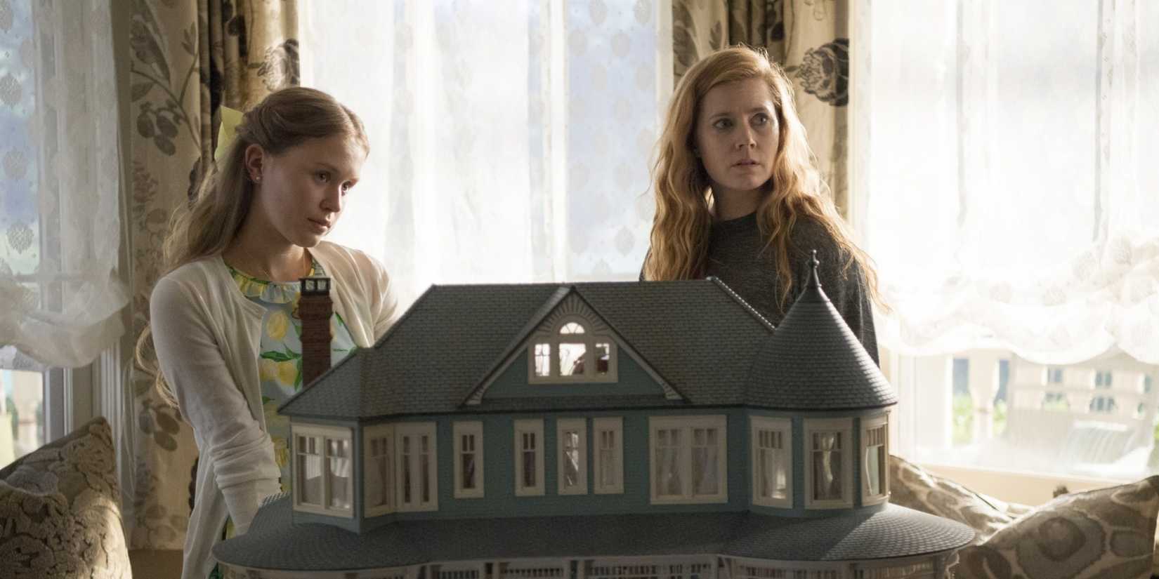Amma Crellin (Eliza Scanlen) e Camille Preaker (Amy Adams) atrás de uma casa de bonecas em Sharp Objects