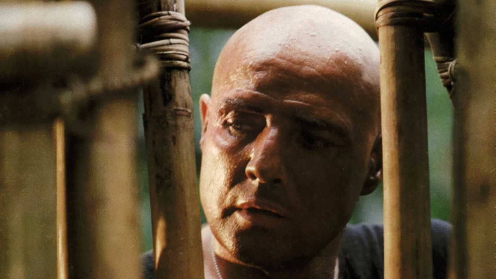 Kurtz looks through the bars of a bamboo cage in Apocalypse Now