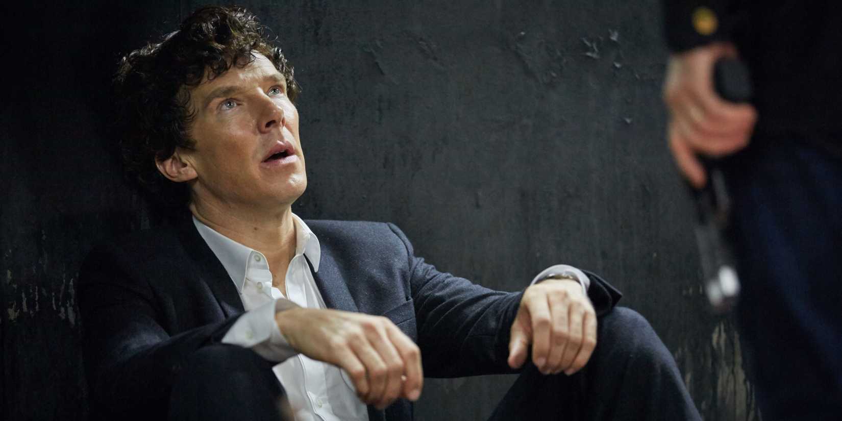 Benedict Cumberbatch as Sherlock Holmes sitting on the floor and looking up in Sherlock