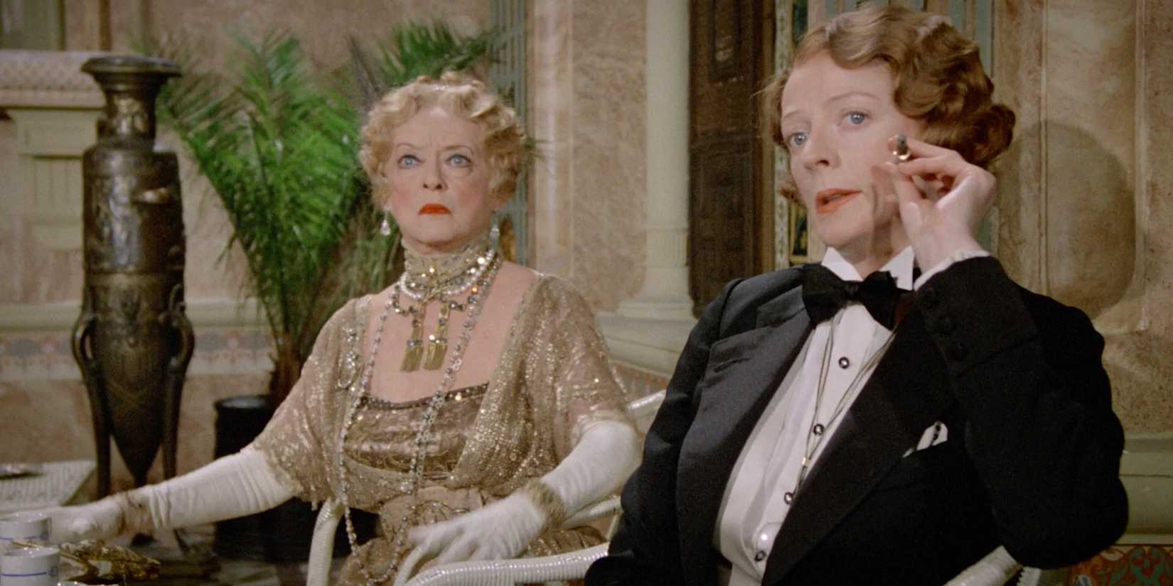 Bette Davis and Maggie Smith look at something with intense interest in a scene from Death on the Nile