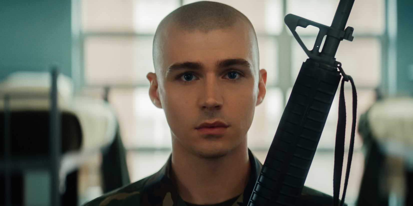 Cam Cope looks straight at the camera and holds up his rifle in Netflix's Boots.