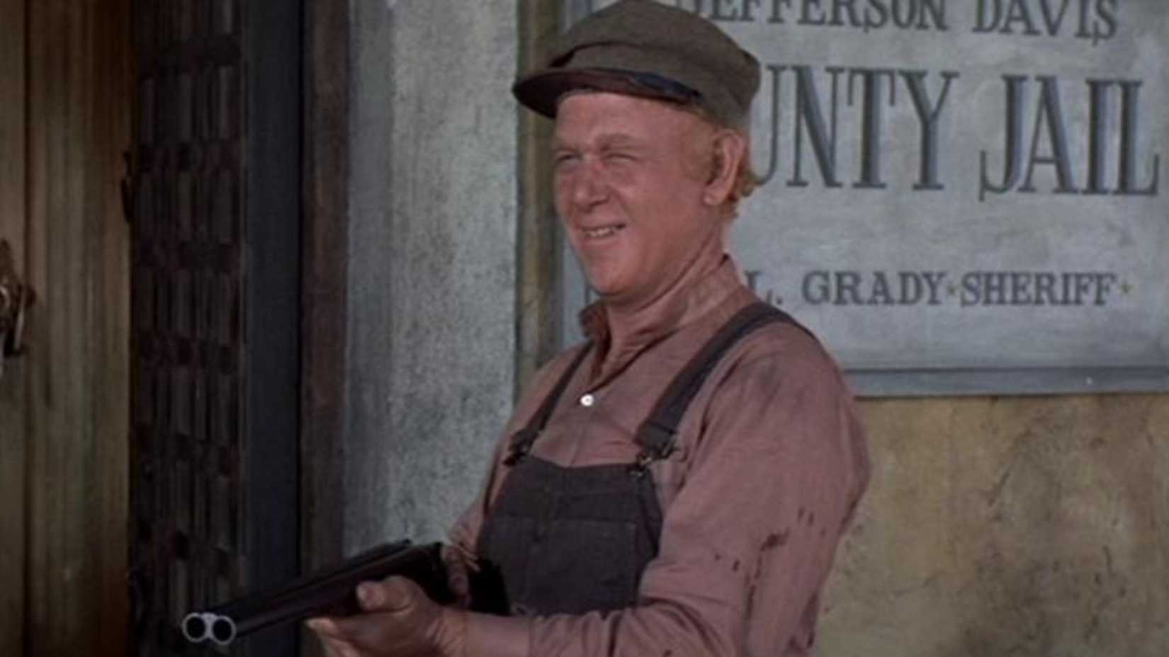 Harry Carey Jr. points a shotgun at someone offscreen in Cahill U.S. Marshall